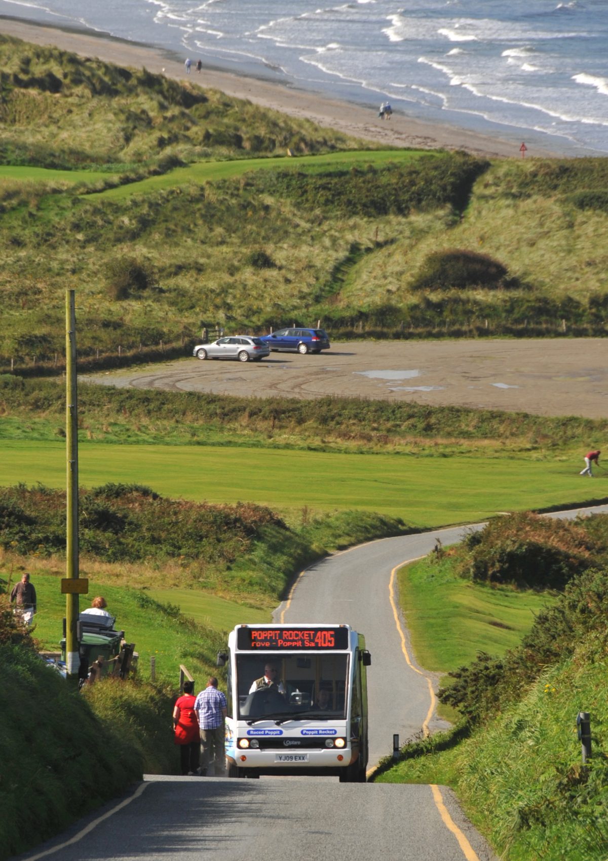 Bus picking up passengers on a narrow coastal road