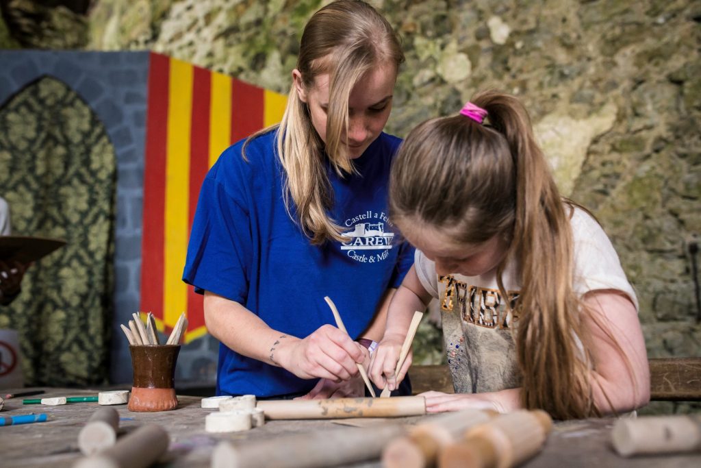 Two girls using a quill pen at Carew Castle