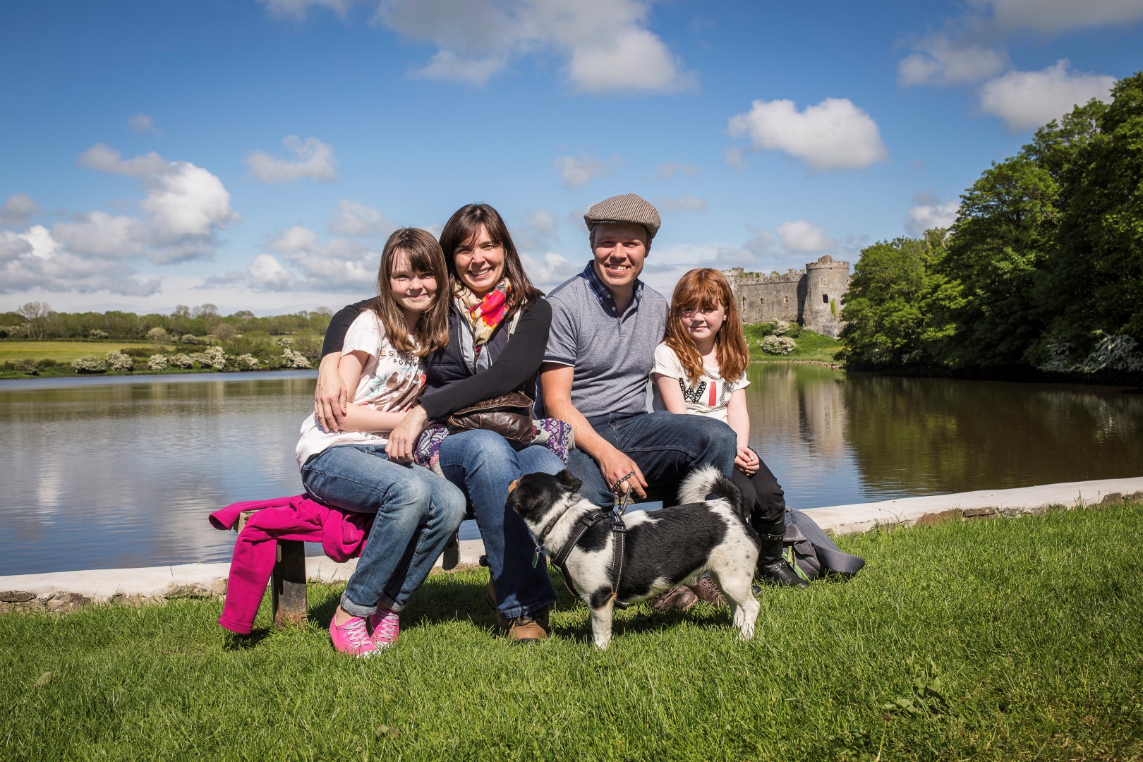 Family of four with dog sitting on Carew millpond with Carew Castle in background
