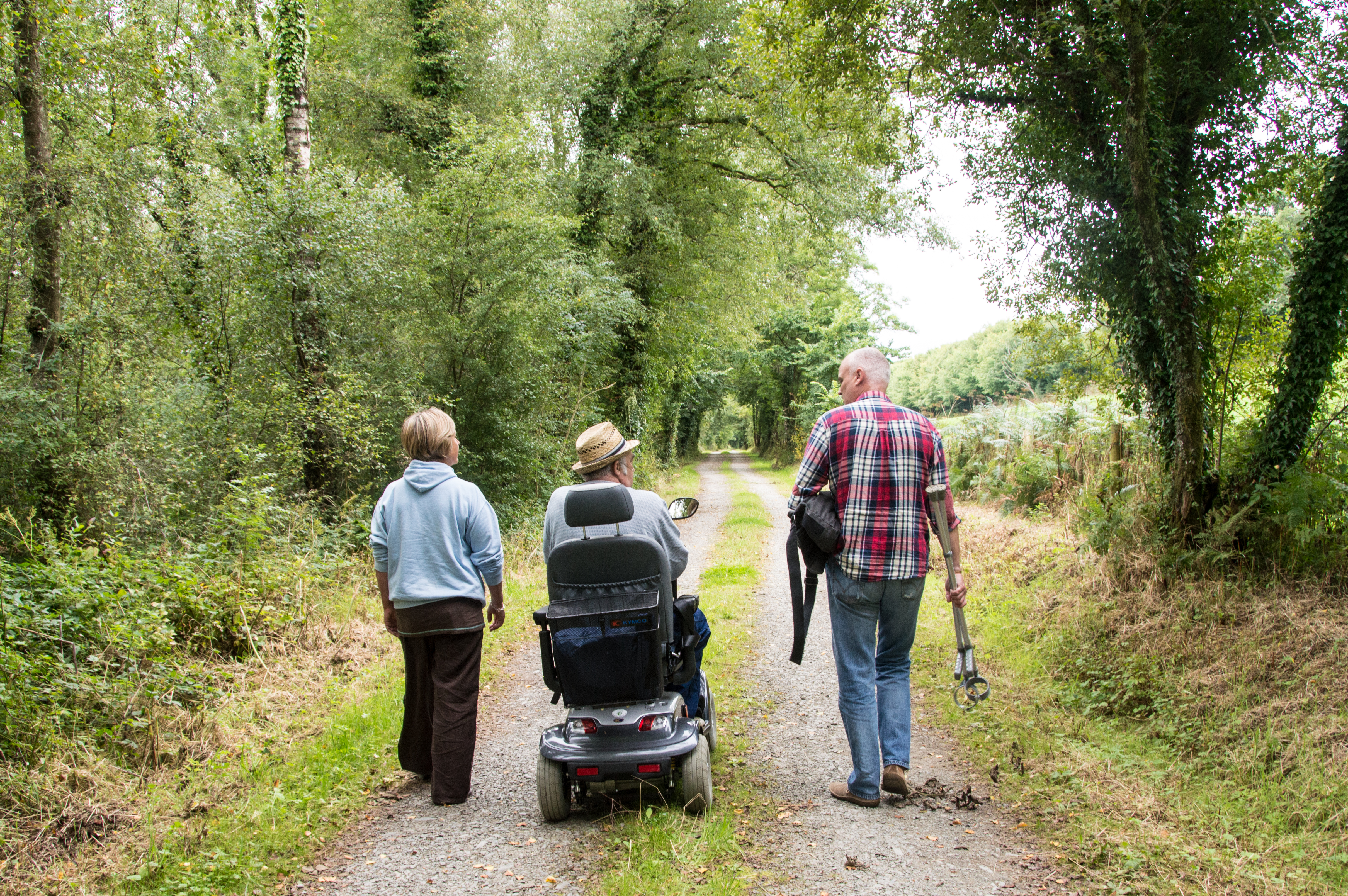 A group of 3 people including a wheelchair user on a country road