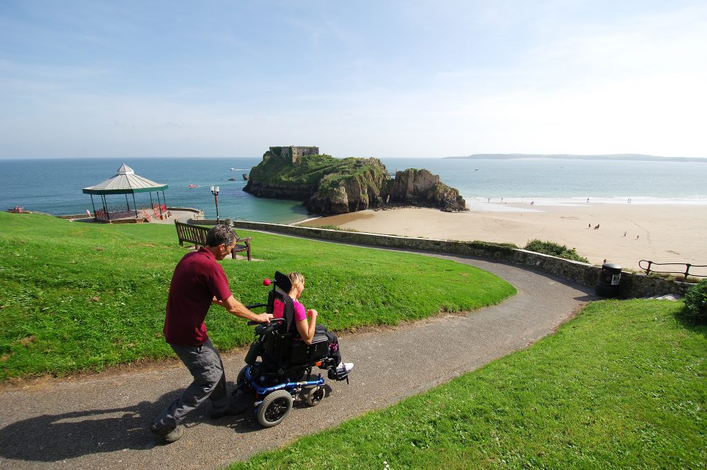 Wheelchair user being pushed on easy access path in Tenby