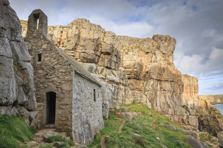 Stone chapel build into a limestone cliff known as St Govan's Chapel in the Pembrokeshire Coast National Park