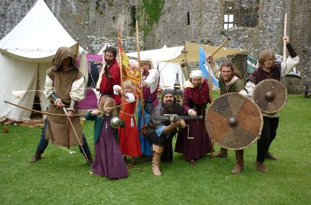Group of people in medieval dress holding bows, swords and shields