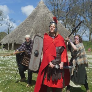 People in Roman costume posing in front of a celtic rooundhouse