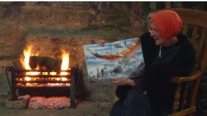 Woman sat by the fire holding a story book