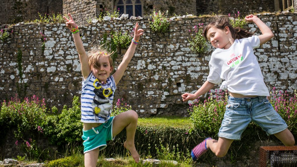 Two girls jumping in front of a stone castle