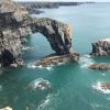 Limestone sea arch reaching from the mainland into the sea with aqua marine seas below. Location pictured is the Green Bridge of Wales, Pembrokeshire