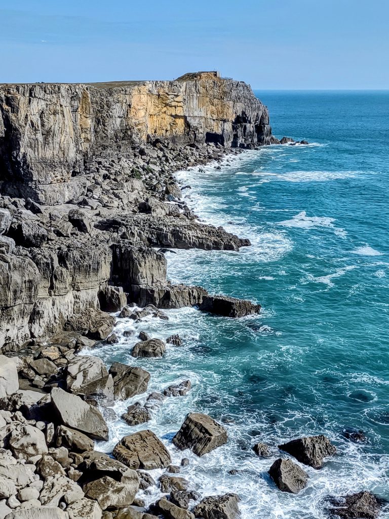 View across limestone cliffs with an aquamarine sea and white waves breaking over the rocks. Location pictures is St Govan&#039;s Head, Pembrokeshire