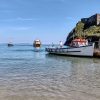 Boat moored next to an island in shallow water with two further boats approaching. Location pictured is Tenby, Pembrokeshire