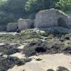Three stone lime kilns in a sandy harbour with rocks covered with seaweed scattered across the dry seabed. Location pictured is Solva, Pembrokeshire