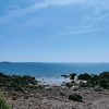 Timy Lyn Dale 2022-02 View from a rocky beach out to see, with four kayaks lying on the sandy area of the beach where the sea is lapping the shore. The sky is blue and sea is reflecting the sunny conditions. Location pictured is on the Dale Peninsula, Pembrokeshire