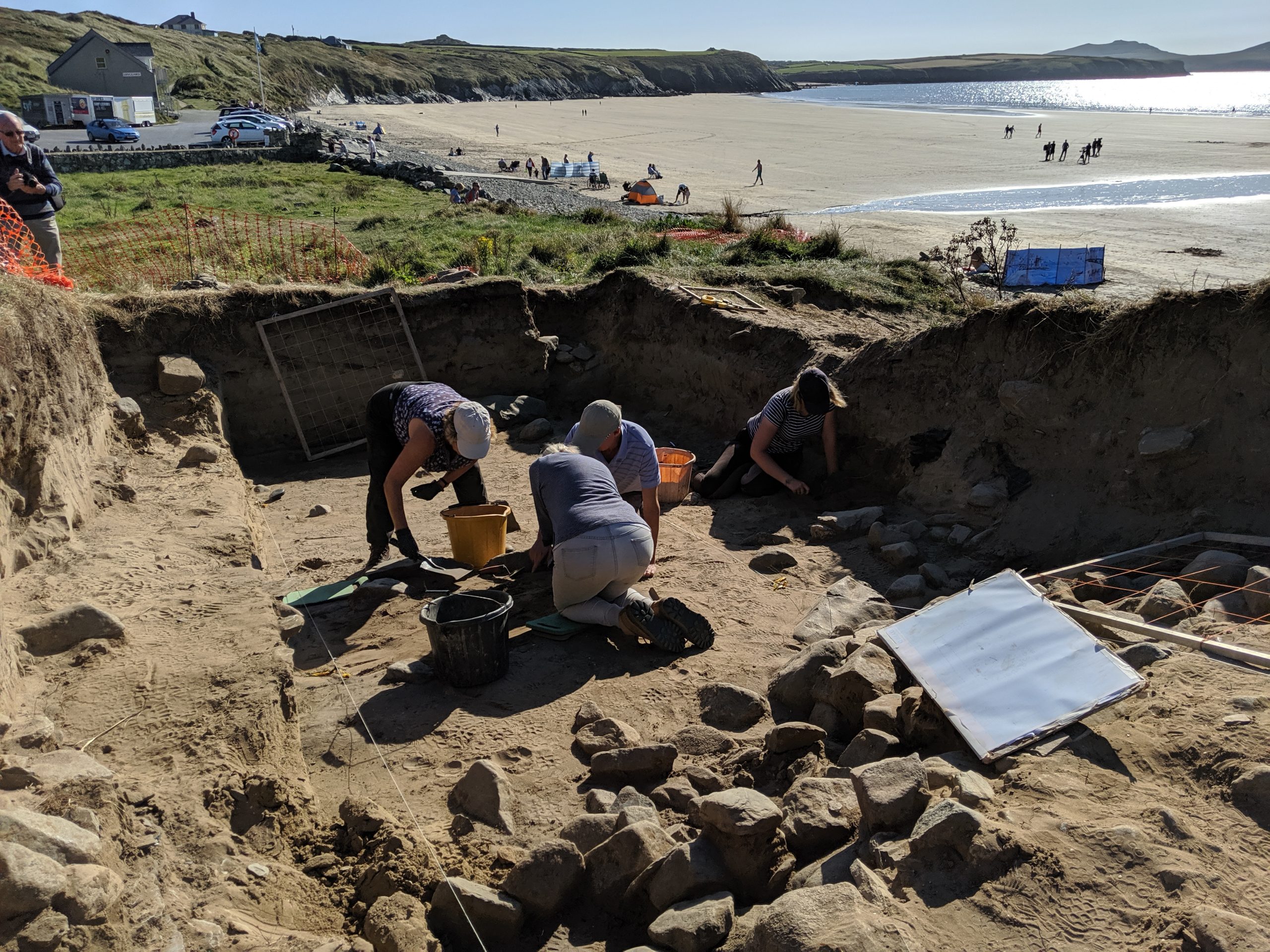 4 people excavating a site as part of an archaeological dig next to a sandy beach. Location pictured is St Patrick's Chapel, Whitesands, St Davids, Pembrokeshire