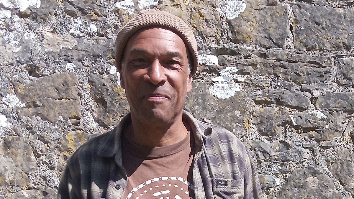 Man standing in front of stone castle wall. Man pictured is Phil Okwendy.