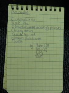 Acrostic poem written in a notepad. It reads: The Cricket Camouflaged in the  Reeds, the Interesting patterened Chirping creature Kicks its legs and Emerges from the  Thicket  by Rosie (13), Billy (8), Lucy and Rich.