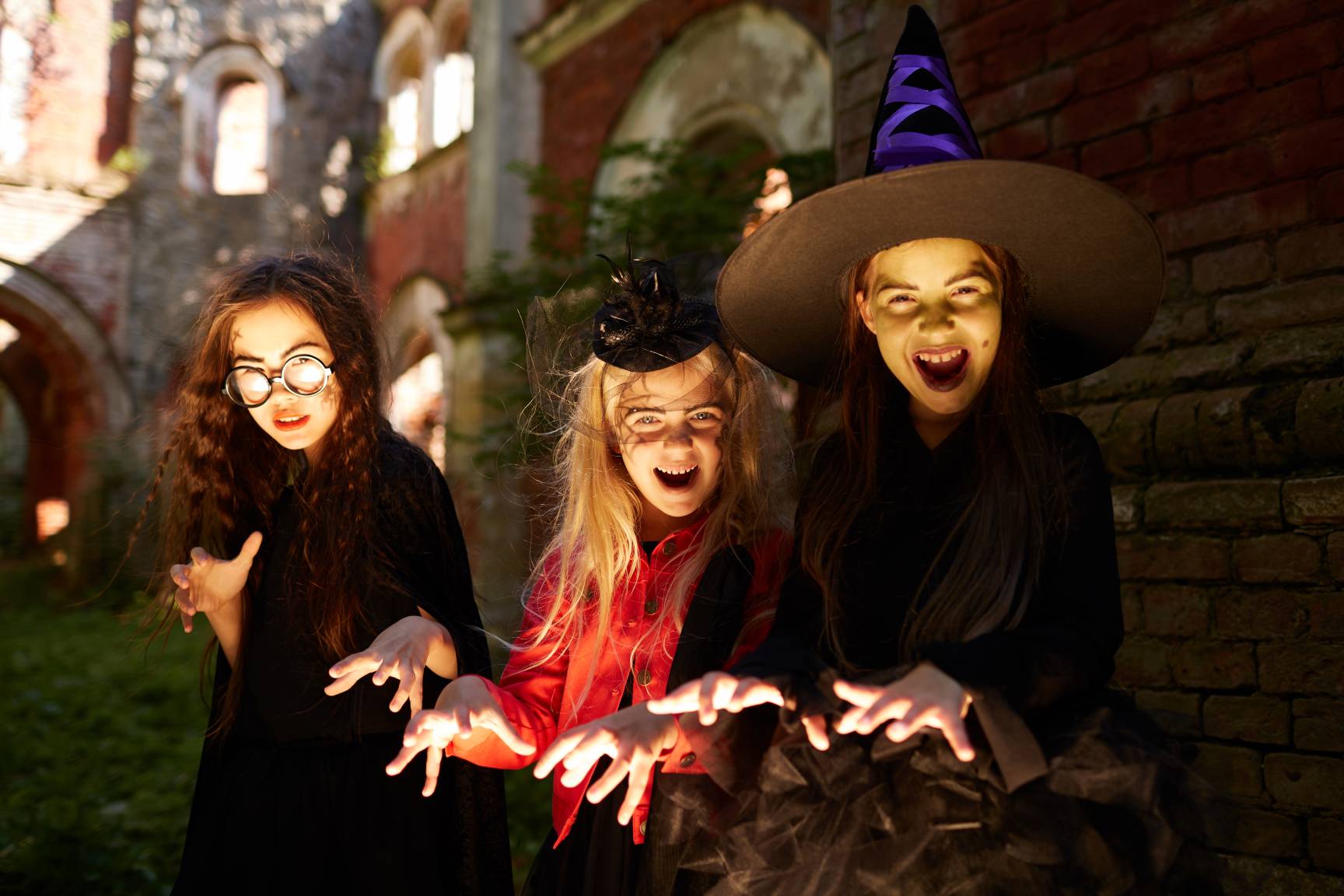 Three girls dressed as witches and pulling scary faces.