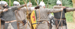 Reenacators in chainmail and helmets firing arrows from bows