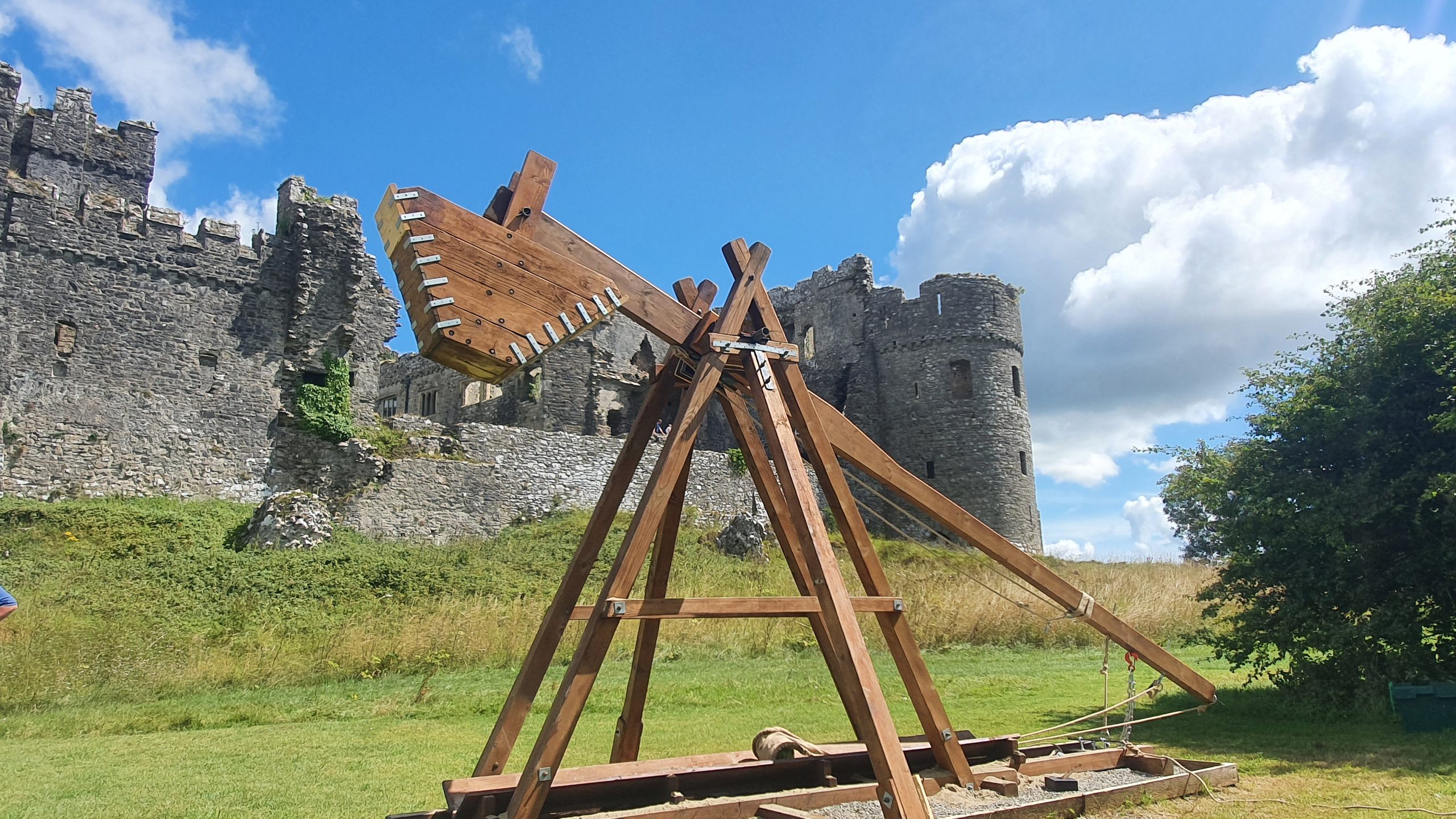 A giant trebuchet with Carew Castle in the background.