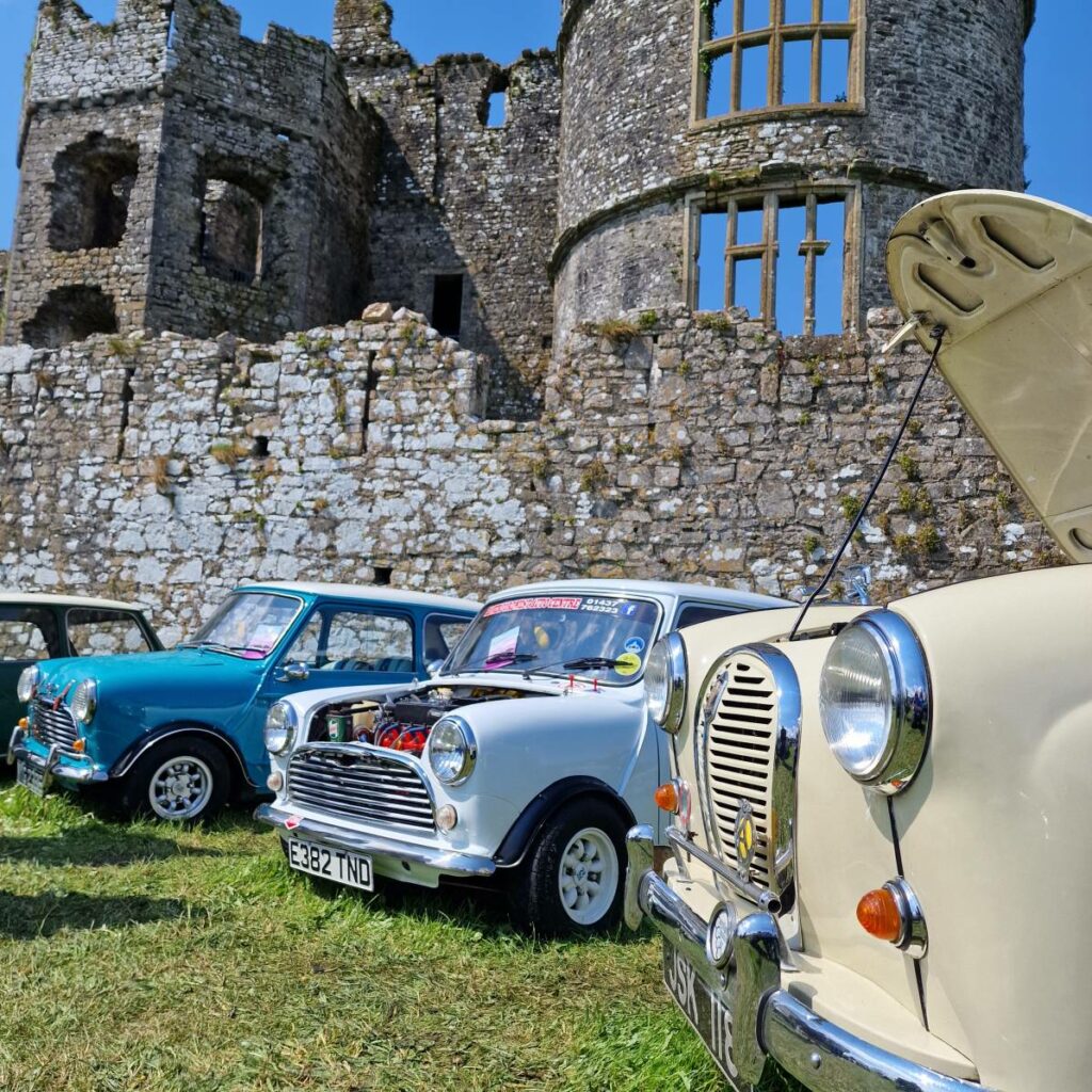 Classic cars parked outside Carew Castle on a sunny day