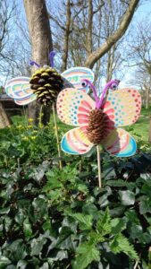 Pine cone sculptures of colourful winged insects.