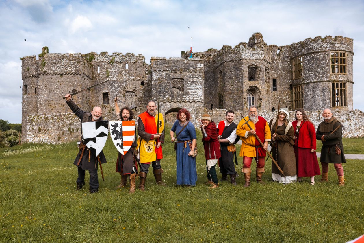 Characters in medieval costume standing in a row outside Carew Castle