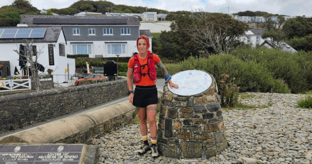 Ultra runner Sanna Duthie stands by the Coast Path marker in her running gear